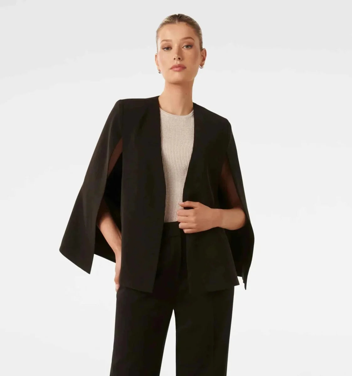 Women's cape blazer styled over tailored trousers for a business look