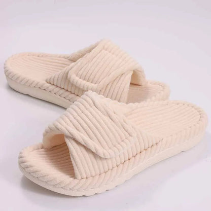 Women wearing open-toe plush house slippers on a bedroom floor