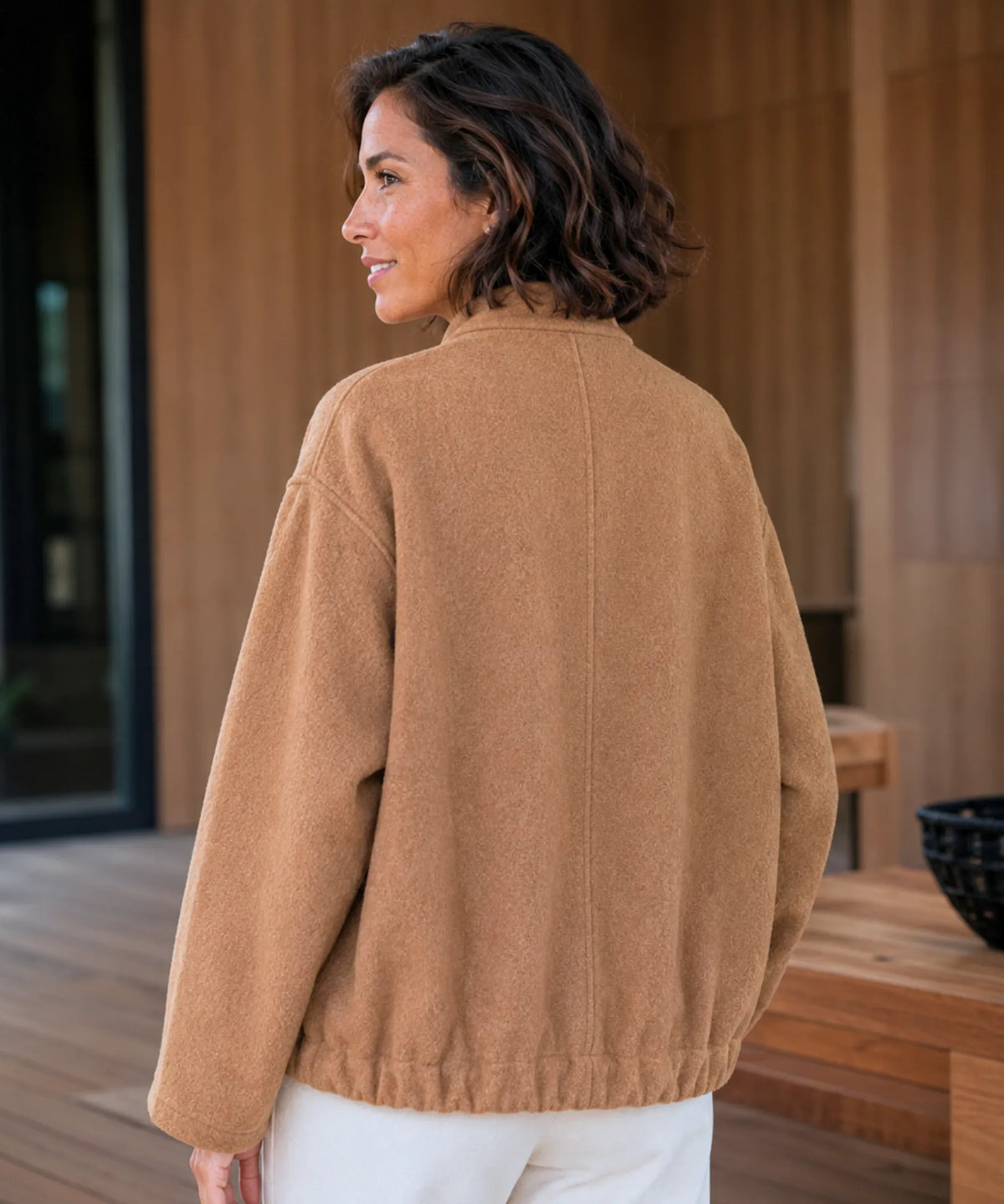 Woman wearing oversized bouclé bomber jacket in nude, casual styling